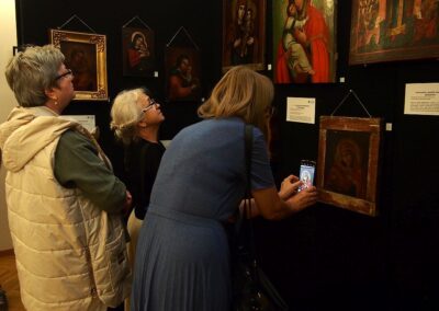 Trzy kobiety przyglądają się ikonom i czytaja opisy.